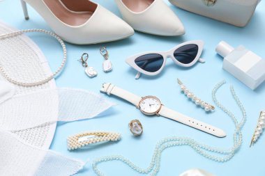 Mavi arka planda güneş gözlüğü, kozmetik ve aksesuarlı kompozisyon. Yakın çekim