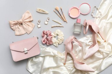 Kozmetik ürünleri, aksesuarlar, gri arka planda fiyonk ve çanta. Üst görünüm