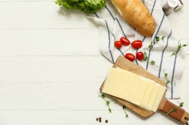 Lezzetli işlenmiş peynir, taze sebze ve ekmek dilimleri beyaz ahşap masada.