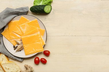 Lezzetli işlenmiş peynir dilimleri ve beyaz ahşap masada taze sebzelerle dolu bir tabak.