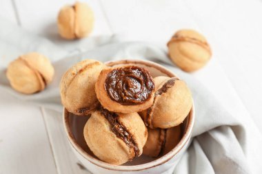 Beyaz ahşap arka planda kaynamış konsantre sütle ceviz şeklinde kurabiyeler.