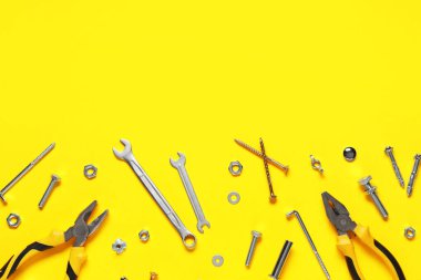 Sarı arka planda tıklama cıvataları, vidalar ve araçlar