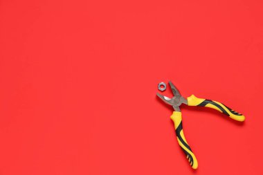 Kırmızı arka planda krom fındıklı pense