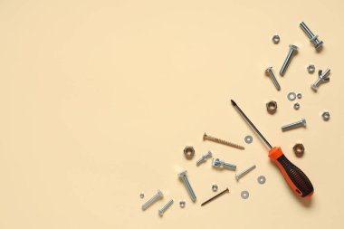 Bej arka planda tıklama cıvataları, vidalar ve tornavida