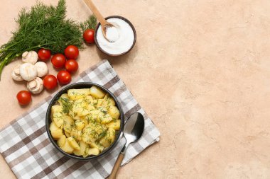 Dereotu, mantar, domates ve bej renginde tuz içeren bir kase lezzetli patates salatası.