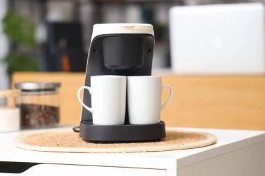 Ofisteki masada fincanlı kahve makinesi, yakın plan.