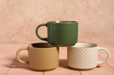 Bej fayans masasında farklı seramik bardaklar