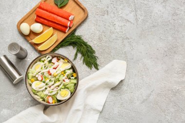 Yengeç saplı bir kase salata, buzdağı yaprakları, mısır, salatalık ve bıldırcın yumurtası gri grunge arka planda.
