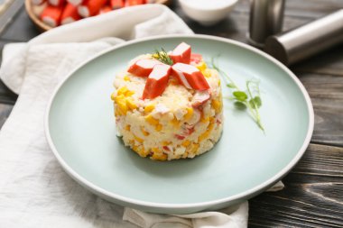 Yengeç çubuklu bir tabak salata ve ahşap zemin üzerinde mısır.