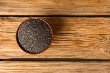 Ahşap arka planda chia tohumları olan bir kase