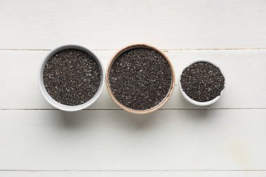 Beyaz ahşap arka planda chia tohumları olan kaseler