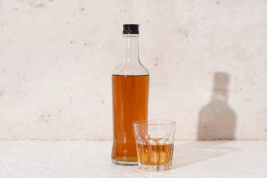 Beyaz zemin üzerinde buz küpleri olan bir şişe rom.