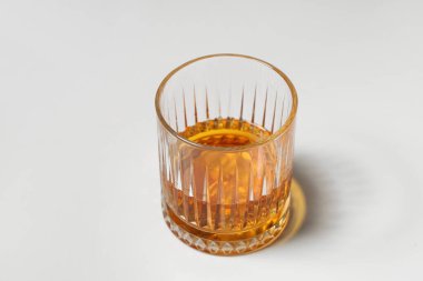 Beyaz zemin üzerinde buz küpleri olan bir bardak rom.