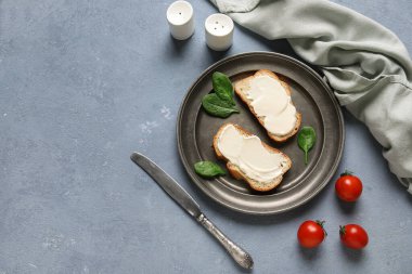 İşlenmiş peynirli lezzetli bruschetta tabağı, ıspanak yaprakları ve mavi arka planda taze domatesler. Üst görünüm