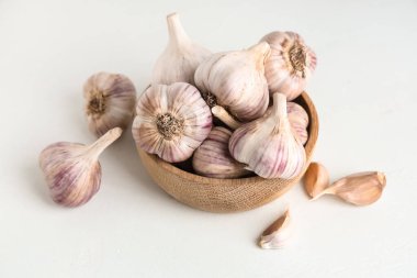 Taze sarımsaklı ahşap kase ve beyaz arka planda karanfil.