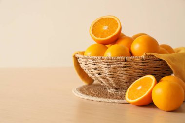 Bej duvarın yanında portakallı hasır kase, yakın plan.