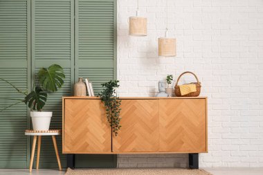 Odanın içinde ahşap klozet, lambalar ve katlanır ekran var.