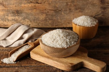 Ahşap zemin üzerinde çiğ pirinç dolu kâseler ve kepçeler.