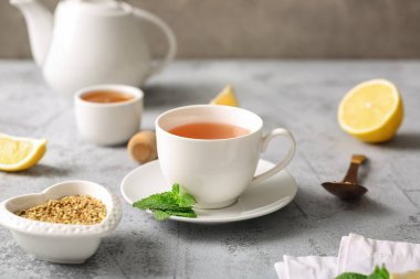 Bir fincan sıcak karabuğday çayı ve gri grunge arka planda nane yaprakları.