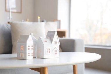 Güzel ev şekilli mum tutucular oturma odasındaki pencerenin yanındaki masada, yakın plan.