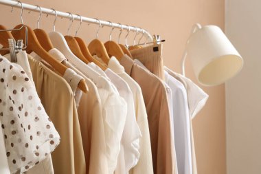 Kahverengi duvarın yanında şık kadın kıyafetleri ve lamba var.