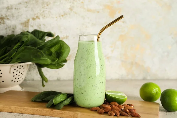 Beyaz arka planda limonlu ve badem fıstıklı bir şişe taze ıspanaklı smoothie.