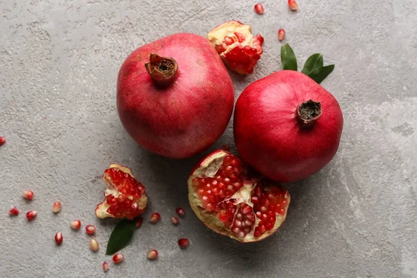 Gri arka planda tohum ve yapraklarla taze olgun narlar.