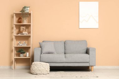 Oturma odasının içinde gri kanepe ve bej duvarın yanında ahşap askı.