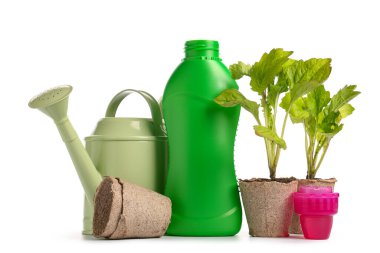 Beyaz zemin üzerinde sulama tenekesi olan bir şişe bitki gübresi.