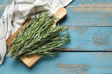 Mavi ahşap arka planda taze biberiye dalları ile kesme tahtası