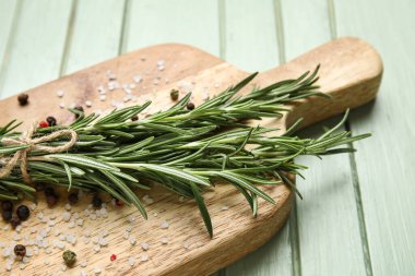 Taze biberiye dallarıyla tahta kesmek, yeşil ahşap arka planda tuz ve biber, yakın plan