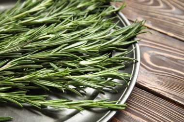 Ahşap arka planda taze biberiye dalları olan tabaklar, yakın plan.