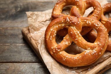 Gri ahşap arka planda lezzetli krakerlerle tahta kesme, yakın plan.