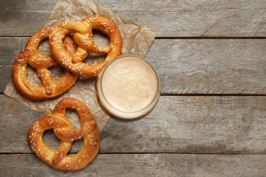 Bir bardak bira ve ahşap arka planda lezzetli krakerler, yakın plan.