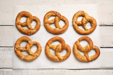 Beyaz ahşap arka planda lezzetli krakerler olan parşömen kağıdı, yakın plan.