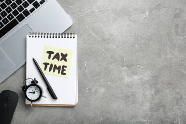 Alarm saati, dizüstü bilgisayarı ve grunge grisi arka planda TAX Time mesajı