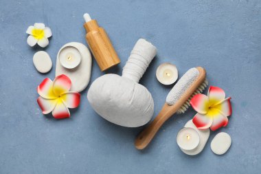 Taşları, bitkisel masaj torbası ve mavi grunge arka planında Plumeria çiçekleri olan güzel bir spa kompozisyonu, yakın plan.