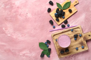 Bir bardak taze böğürtlen suyu ve pembe arka planda yaban mersini.