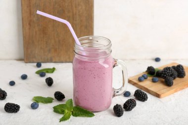 Mason kavanozu taze böğürtlenli, naneli ve yaban mersinli meyve püresi.