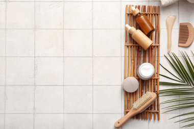 Bambu tepsisi, tropikal yaprak, şişe ve kozmetik ürünler içeren kaplıca kompozisyonu beyaz karo arka planda, yakın plan