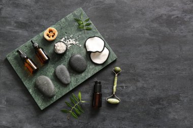 Tepsisi, taşı, siyah grunge arka planında kozmetik ürünleri olan spa kompozisyonu