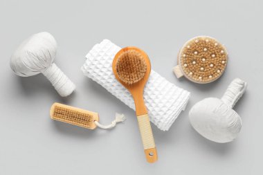 Beden masajı fırçaları ve gri arka planda bitki torbaları.