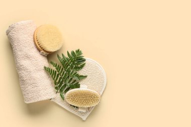 Eldiven, havlu ve arka planda taze yaprak ile vücut masajı fırçaları.