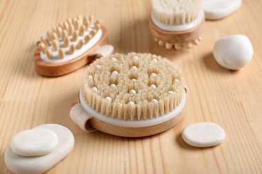 Tahta arka planda vücut masajı fırçaları ve spa taşları, yakın plan.