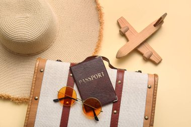 Bej arka planda bavul, pasaport, oyuncak uçak ve plaj aksesuarları, yakın plan.
