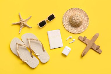 Sarı arka planda pasaport, kulaklık ve plaj aksesuarları, yakın plan.
