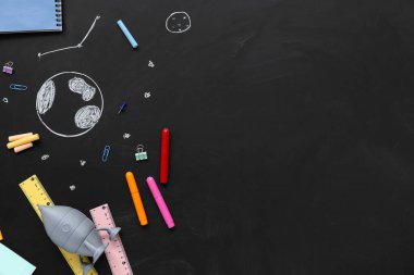 Oyuncak roketli farklı kırtasiye malzemeleri ve siyah karatahtaya çizimler.