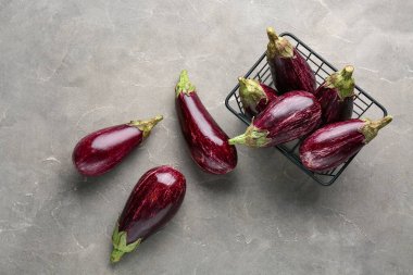 Gri arka planda taze olgun patlıcanlarla dolu sepet.