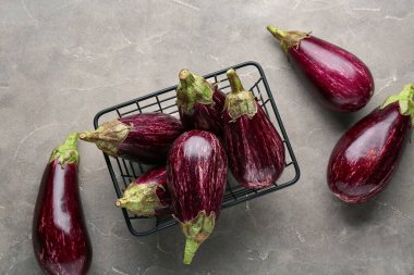 Gri arka planda taze olgun patlıcanlarla dolu sepet.