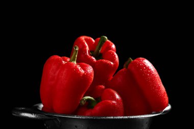 Siyah arka planda kırmızı dolma biberli Colander.